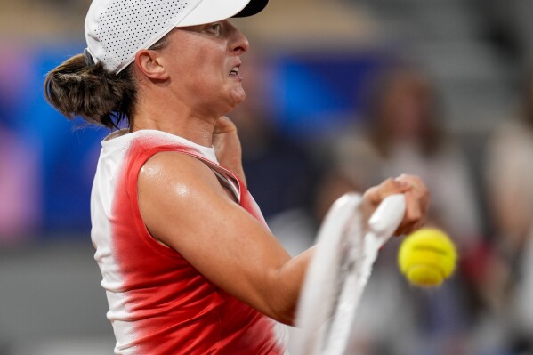 Iga Swiatek of Poland returns the ball against Irina-Camelia Begu of Romani during a women's singles tennis competition, at the 2024 Summer Olympics, Saturday, July 27, 2024, in Paris, France. (AP Photo/Manu Fernandez)