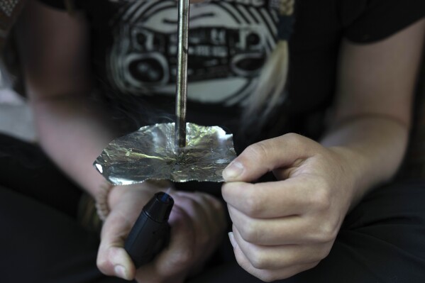 FILE - A homeless woman smokes fentanyl in a park on June 28, 2024, in downtown Portland, Ore. (AP Photo/Jenny Kane, File)