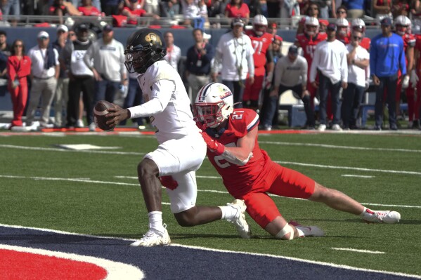 Colorado quarterback Shedeur Sanders scores a touchdown as Arizona defensive back Owen Goss (27) tries to make the tackle in the first half during an NCAA college football game, Saturday, Oct. 19, 2024, in Tucson, Ariz. (AP Photo/Rick Scuteri)