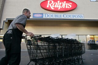 FILE -Francisco Luna collects shopping carts outside of a Ralphs grocery store in Los Angeles on Monday, Dec. 5, 2005. California sued the Ralphs supermarket chain on Thursday, Ded. 21, 2023, alleging that it violated state law by asking job-seekers whether they had criminal records and illegally rejecting hundreds of applicants (AP Photo/Kevork Djansezian, File)