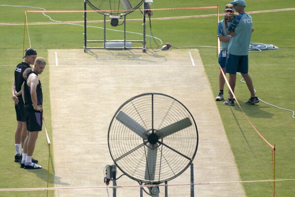 England's Brydon Carse, left, Olly Stone, second left, and Pakistan's coach Jason Gillespie, right, examine the pitch preparing for upcoming third test match between Pakistan and England, in Rawalpindi, Pakistan, Tuesday, Oct. 22, 2024. (AP Photo/Anjum Naveed)