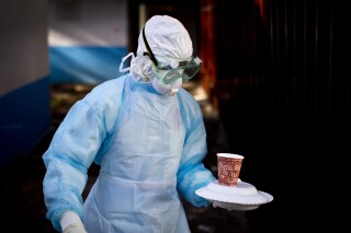 FILE - In this Oct. 8, 2014 photo, a medical worker from the Infection Prevention and Control unit wearing full protective equipment carries a meal to an isolation tent housing a man being quarantined after coming into contact in Uganda with a carrier of the Marburg Virus, at the Kenyatta National Hospital in Nairobi, Kenya. (AP Photo/Ben Curtis, File)