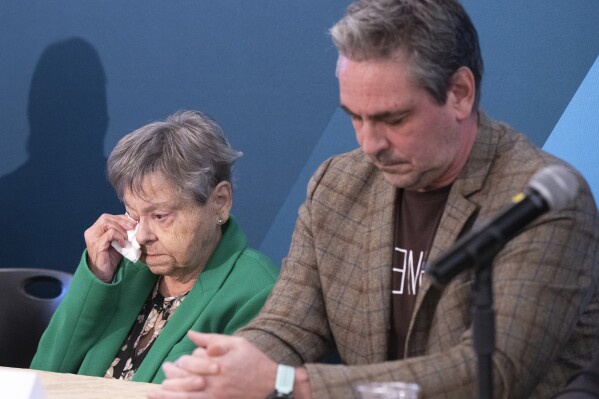 Lise Blais, widow of plaintiff Jean-Yves Blais, wipes her eye as her son, Martin, looks on during a news conference, in Montreal, on Friday, Oct. 18, 2024. Tobacco companies have offered to pay nearly $24 billion USD in compensation to smokers and their loved ones. (Ryan Remiorz/The Canadian Press via AP)