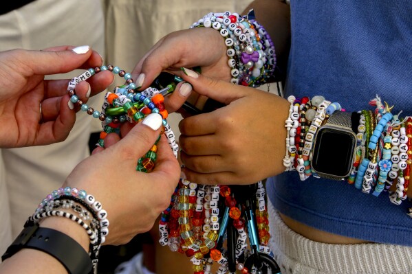 Swifties, a term for Taylor Swift fans, trade bracelets in the city centre in Vienna on Thursday, Aug.8, 2024. Organizers of three Swift concerts in the stadium in Vienna this week called them off on Wednesday after officials announced arrests over an apparent plot to launch an attack on an event in the Vienna area such as the concerts. (AP Photo/Heinz-Peter Bader)