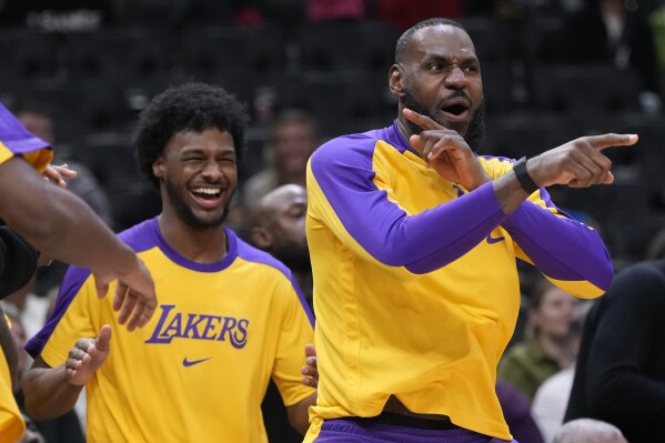 Los Angeles Lakers' LeBron James and Bronny James react on the bench during the second half of an NBA preseason basketball game against the Milwaukee Bucks Thursday, Oct. 10, 2024, in Milwaukee. (AP Photo/Morry Gash)