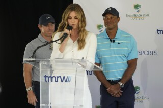 Host Erin Andrews, center, introduces golfers Tiger Woods, right, and Rory McIlroy during a news conference announcing the future home of TGL, a new tech-infused, team golf league, Tuesday, Feb. 21, 2023, on the campus of Palm Beach State College in Palm Beach Gardens, Fla. (AP Photo/Wilfredo Lee)