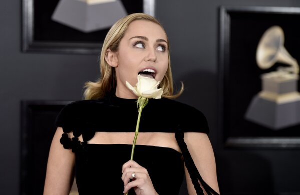 
              Miley Cyrus holds a white rose as she arrives at the 60th annual Grammy Awards at Madison Square Garden on Sunday, Jan. 28, 2018, in New York. (Photo by Evan Agostini/Invision/AP)
            