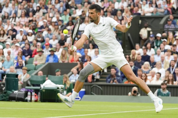 Serbia's Novak Djokovic plays a backhand return to Vit Kopriva of the Czech Republic during their first round match at the Wimbledon tennis championships in London, Tuesday, July 2, 2024. (AP Photo/Kirsty Wigglesworth)