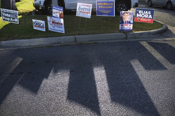 FILE - Campaign signs for candidates cast a shadow on the street during early voting at Lark Library, Oct. 21, 2024, in McAllen, Texas. (Delcia Lopez/The Monitor via AP, File)