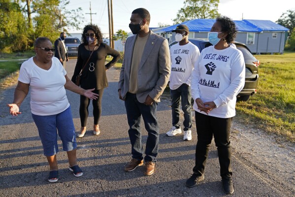 FILE - EPA Administrator Michael Regan talks with Brenda Bryant, left, and other members of the group Rise St. James, as he tours a neighborhood next to the Nu Star Energy oil storage tanks, in St. James Parish, La., on Nov. 16, 2021. (AP Photo/Gerald Herbert, File)