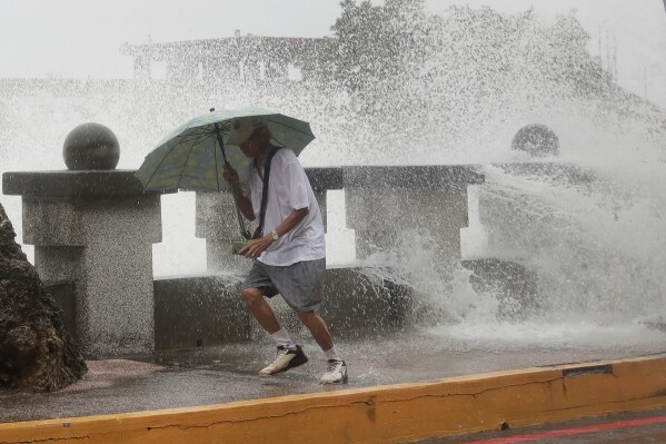 A man runs away from waves when he was walking along the shore in Kaohsiung, Southern Taiwan, Wednesday, Oct. 2, 2024, as Typhoon Krathon is expected to hit the area. (AP Photo/Chiang Ying-ying)