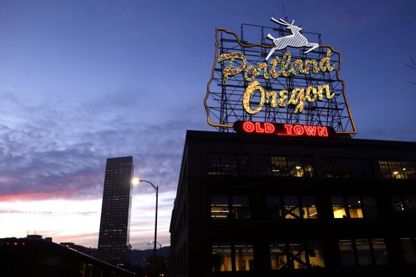 FILE - The "Portland, Oregon" sign is illuminated in with the Wells Fargo Center building in the background in downtown Portland, Ore., Jan. 27, 2015. (AP Photo/Don Ryan, File)