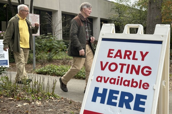 People leave after voting in the Atlanta suburb of Sandy Springs, Ga., on Tuesday, Oct. 15, 2024, the first day of early in-person voting in Georgia. (AP Photo/Jeff Amy)