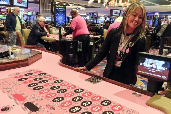 Lee Johnson, a games manager at the Hard Rock casino, checks a roulette table covered in pink felt for breast cancer awareness month before it opens for use in Atlantic City, N.J., Thursday, Oct. 3, 2024. (AP Photo/Wayne Parry)