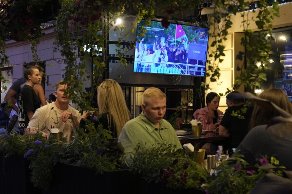 People watch the television broadcast of the opening ceremony of the 2024 Summer Olympics in Paris, France via Kazakhstan satellite channel sitting in the Waterloo pub & bar in St. Petersburg, Russia, Friday, July 26, 2024. Watching the Paris Olympics will be difficult for most people in Russia, and in the view of local media it's not really worth the effort. Russia's state TV channels won't be broadcasting any of the events. (AP Photo/Dmitri Lovetsky)