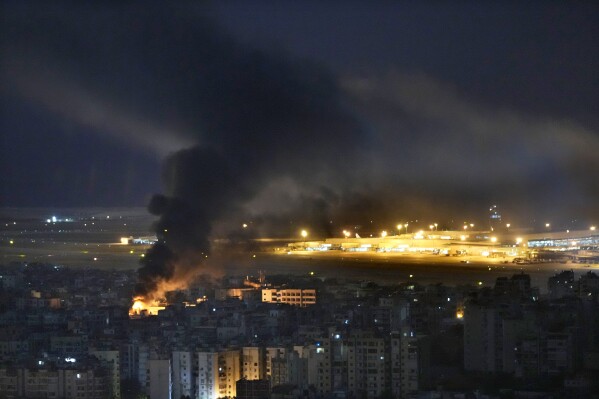 Flames and smoke rise form an Israeli airstrike, as Rafik Hariri international airport seen on the background, in the southern suburb of Beirut, Lebanon, Sunday, Oct. 20, 2024. (AP Photo/Hussein Malla)