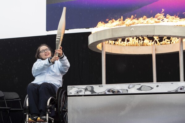 British Paralympian Helene Raynsford holds the Paralympic Torch during the flame lighting ceremony in Stoke Mandeville, widely considered the birthplace of the Paralympic Games, England, Saturday, Aug. 24, 2024. (AP Photo/Thomas Krych)