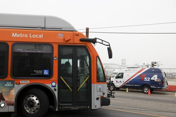 A bus passes by a news van in front of a Los Angeles MTA bus depot near the site where overnight a bus was hijacked by an armed subject with passengers on board Wednesday, Sept. 25, 2024, in Los Angeles. (AP Photo/Ryan Sun)