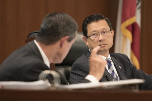 FILE - Supervisor Andrew Do, right, listens to Supervisor Todd Spitzer, left, during questioning of Orange County District Attorney Tony Rackauckas in front of the Orange County Board of Supervisors meeting in Santa Ana on June 27, 2017. (Sam Gangwer/The Orange County Register via AP, fIle)