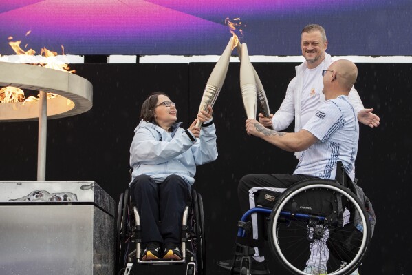 FILE - British Paralympians Helene Raynsford and Gregor Ewan light the Paralympic Flame in Stoke Mandeville, widely considered the birthplace of the Paralympic Games, England, Saturday, Aug. 24, 2024. The Paralympic Games are set to open Wednesday as some 4,400 athletes with disabilities, permanent injuries or impairments prepare to compete for 549 medals across 22 sports over 11 days in Paris. (AP Photo/Thomas Krych, File)