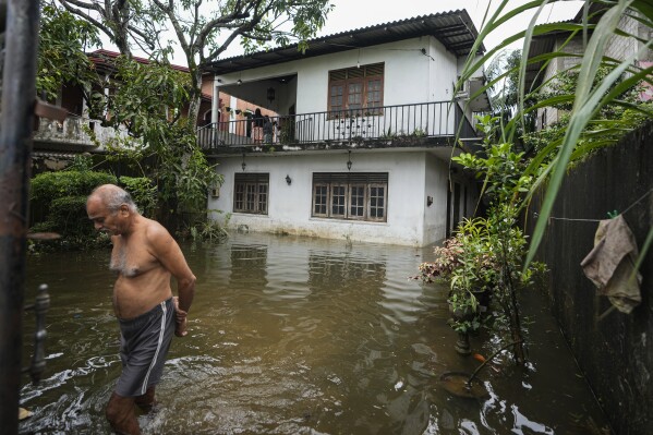 A man wades through his flooded neighborhood in Colombo, Sri Lanka, Monday, Oct. 14, 2024. (AP Photo/Eranga Jayawardena)