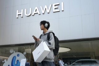 FILE - A customer carries his purchased Huawei product outside a Huawei store after he attended the Huawei new product launch conference in Beijing, on Sept. 25, 2023. Chinese telecoms gear company Huawei Technologies has reported its profit more than doubled last year as its cloud and digital businesses thrived in spite of U.S. sanctions. (AP Photo/Andy Wong, File)