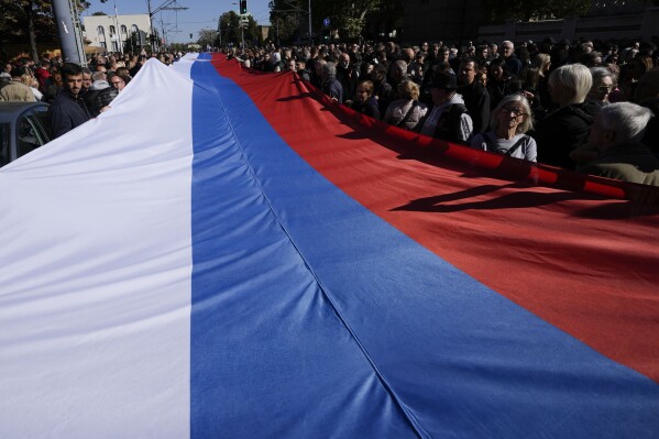 People hold a giant Serbian flag during the ceremony on the occasion of the 80th anniversary of the liberation of Belgrade from Nazi occupation in WWII by Soviet and local communist fighters, in Belgrade, Serbia, Sunday, Oct. 20, 2024. (AP Photo/Darko Vojinovic)