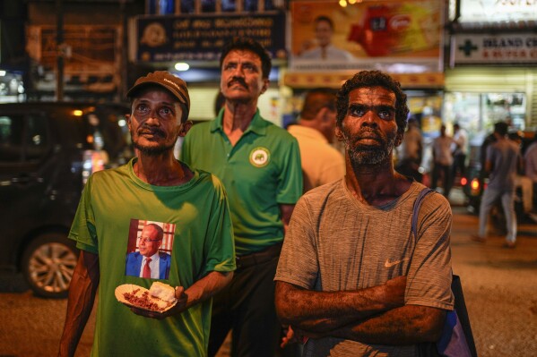 Supporters of Sri Lanka's President Ranil Wickremesinghe watch a televised speech in Colombo, Sri Lanka, Wednesday, June 26, 2023. President Ranil Wickremesinghe in a televised address to the nation announced that the country had reached agreements with bilateral creditors including Japan, India, France and China, a key step in the island nation's economic recovery since defaulting on its debt repayment in 2022. (AP Photo/Eranga Jayawardena)