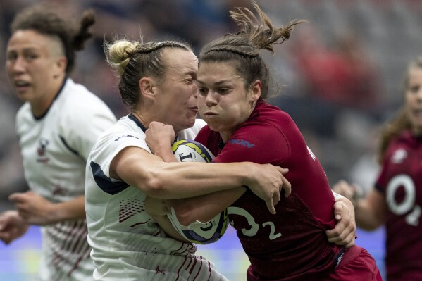 England's Helena Rowland, front right, runs through United States' McKenzie Hawkins, front left, during WXV 1 women's rugby union match action in Vancouver, British Columbia, Sunday, Sept. 29, 2024. (Ethan Cairns/The Canadian Press via AP)