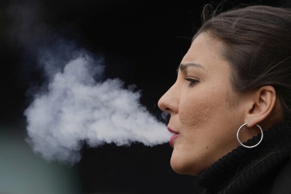 A woman smokes on a street, in London, Tuesday, April 16, 2024. A bold plan to ban anyone born after 2008 from ever legally buying cigarettes in Britain faces its first test in Parliament. The bold plan has divided the governing Conservatives, with some hailing its public health benefits and others condemning it as state overreach. (AP Photo/Kin Cheung)