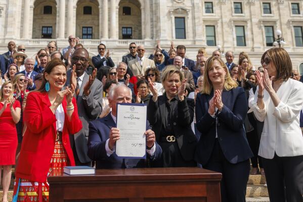 Minnesota Gov. Tim Walz proudly displays the One Minnesota Budget bill after signing it into law, Wednesday, May 24, 2023, outside the Minnesota State Capitol in St. Paul, Minn. (Kerem Yücel/Minnesota Public Radio via AP)