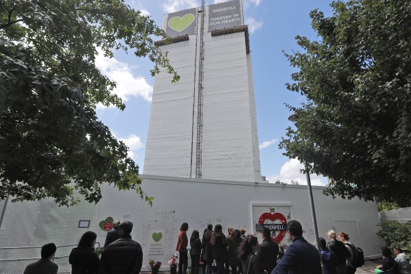 FILE - People pay their respects at the Grenfell tower to mark the two-year anniversary of the Grenfell Tower block fire, in London, Friday, June 14, 2019. (AP Photo/Frank Augstein, File)