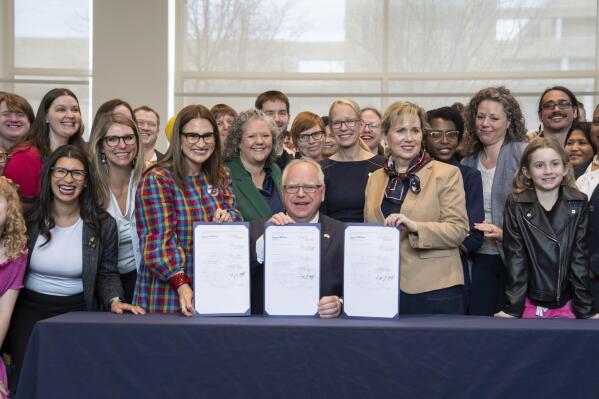 Minnesota Gov. Tim Walz, poses with supporters after he signed three progressive priorities, a ban on conversion therapy for minors and vulnerable adults, and two bills that would make Minnesota a refuge for people traveling here for abortion and gender affirming care, Thursday, April 27, 2023, in St. Paul, Minn. (Glen Stubbe/Star Tribune via AP)