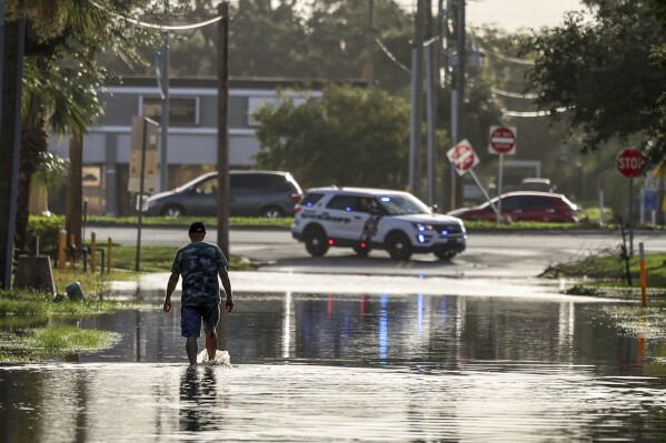 A man walks out of a street with water flooded from Hurricane Helene Friday, Sept. 27, 2024, in New Port Richey, Fla. (AP Photo/Mike Carlson)