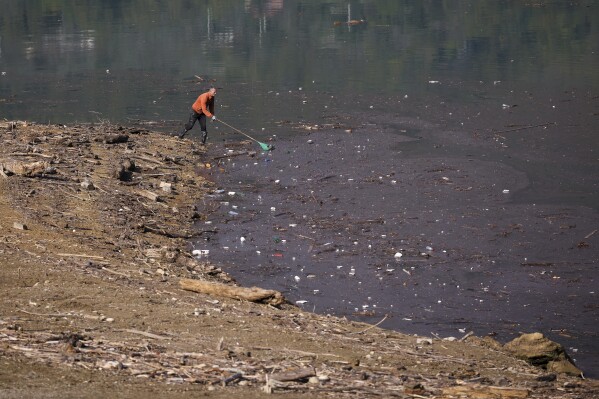 Dervis Gabela collects plastic waste from the shore after devastating floods and landslides put tons of waste in Jablanicko lake near Ostrozac, Bosnia, Sunday, Oct. 20, 2024. (AP Photo/Armin Durgut)